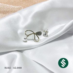 Khuyên tai không đối xứng hai bên, dáng nơ to đính ngọc và bên còn lại là đá xanh sáng bóng cực đẹp